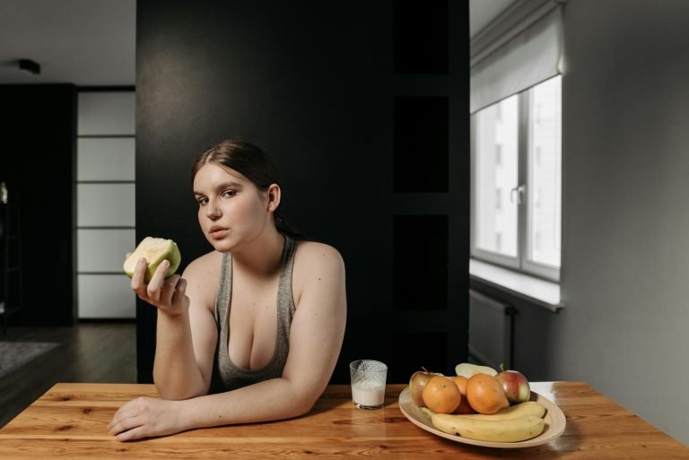 Woman enjoying an apple and glass of milk, promoting a healthy lifestyle indoors.