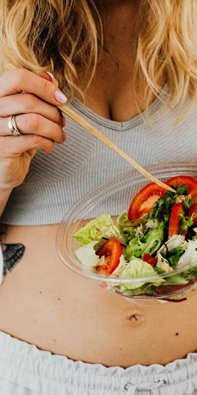 Woman in sports attire enjoys a fresh, nutritious salad, embodying a healthy lifestyle.