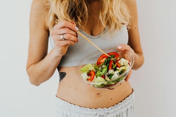 Woman in sports attire enjoys a fresh, nutritious salad, embodying a healthy lifestyle.