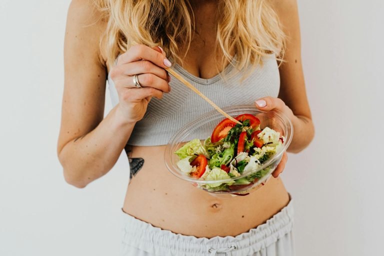 Woman in sports attire enjoys a fresh, nutritious salad, embodying a healthy lifestyle.