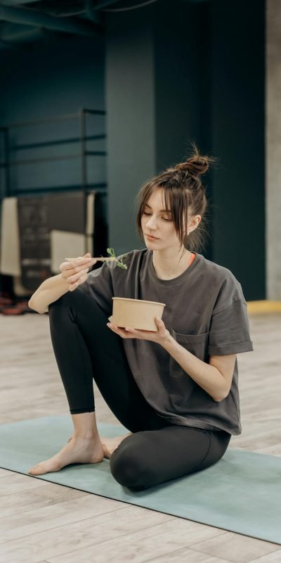 Young woman eating a healthy meal after a yoga workout at the gym.